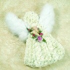 Angel-shaped funeral tribute with white chrysanthemum base, soft feather wings and a pink floral focal arrangement.
